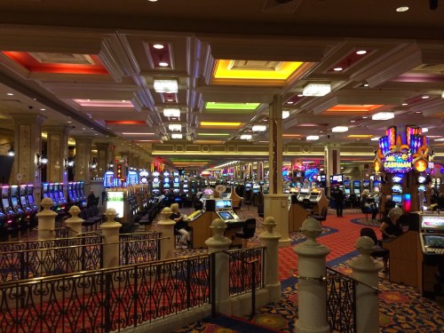 A vibrant casino interior filled with colorful slot machines and bright lights, bustling with activity.