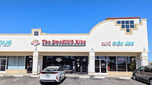 Exterior of a building featuring "The Smokin' Ribs BBQ Restaurant" and "Café Diên Anh" with parked cars in front.