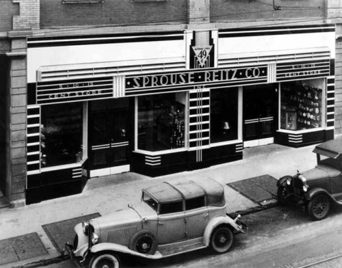 Historic storefront of Sprouse-Reitz Co. featuring Art Deco design, with vintage cars parked outside.