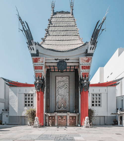 A grand Chinese theater with ornate architecture, featuring a large entrance and decorative statues on either side.