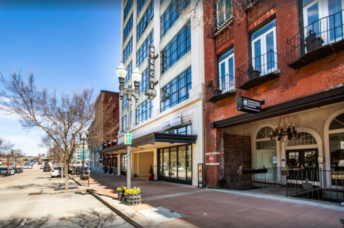 A city street view featuring buildings, storefronts, and clear blue skies.