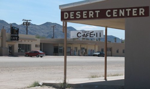 A view of Desert Center, featuring a café and surrounding buildings against a backdrop of mountains.