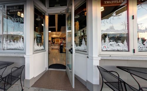 A welcoming café entrance with festive window decorations and an open door inviting customers inside.