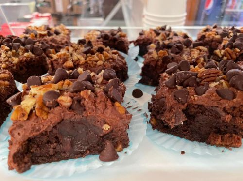 Close-up of chocolate brownies topped with nuts and chocolate chips, displayed on a tray.