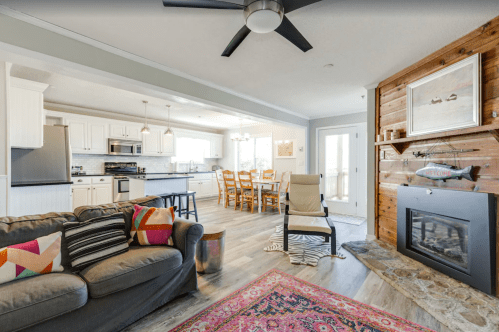 Cozy living space with a sofa, dining area, and modern kitchen, featuring wood accents and a fireplace.