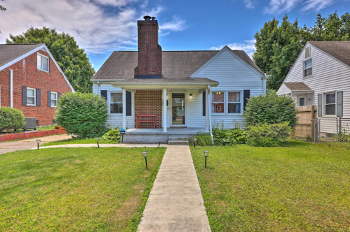 A charming single-story house with a front porch, surrounded by greenery and a clear blue sky.