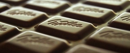 Close-up of a Milka chocolate bar, showcasing its smooth surface and embossed logo on the chocolate pieces.