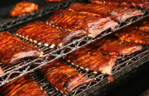 Grilled ribs arranged on a rack, showcasing a rich, smoky glaze and charred edges.