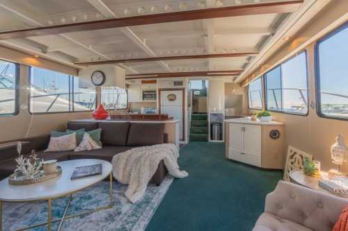 Cozy yacht interior featuring a living area, kitchen, and large windows with a view of the marina.