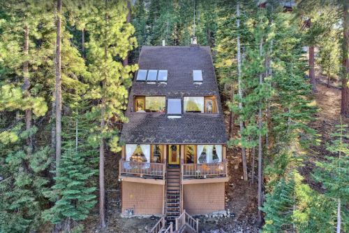A cozy cabin nestled among tall pine trees, featuring a sloped roof and large windows.