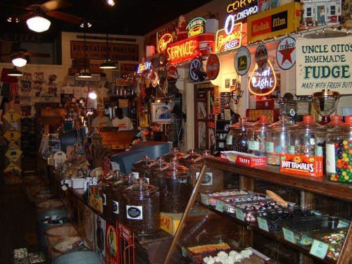 A vintage store filled with colorful neon signs, jars of candy, and nostalgic memorabilia on display.