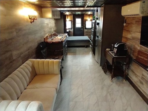 A cozy interior of a small living space featuring a sofa, kitchen area, and a bed in a stylish, modern design.