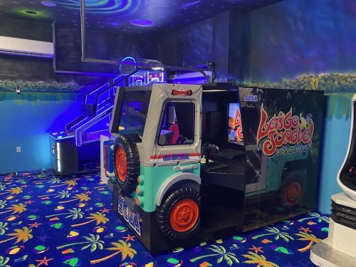 A colorful arcade room featuring a "Lost in Jungle" arcade game cabinet and vibrant patterned carpet.