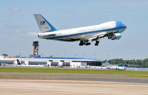 A large airplane with "United States of America" on its side takes off from an airport runway.