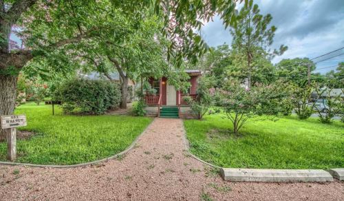 A charming house surrounded by lush greenery and a gravel pathway leading to the entrance.