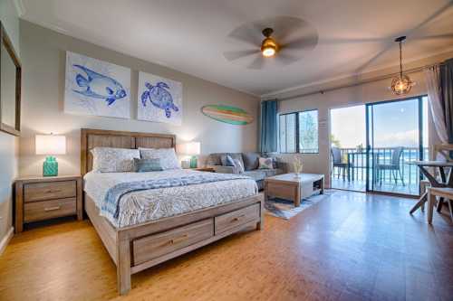 Cozy bedroom with a wooden bed, ocean-themed decor, and large windows overlooking a balcony with a sea view.