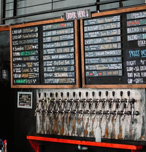 A wall-mounted menu board with various beer options and a row of taps below, labeled "Order Here."