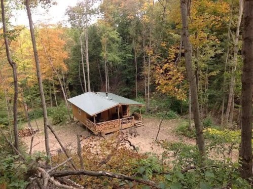 A cozy cabin surrounded by colorful autumn trees in a serene forest setting.
