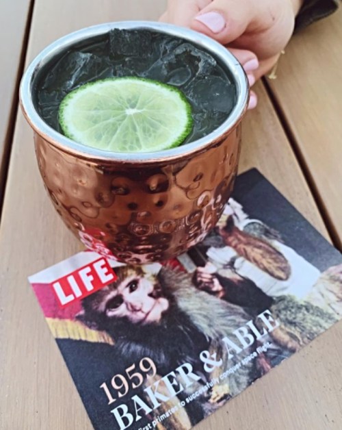 A copper mug filled with a dark drink and a lime slice, resting on a magazine featuring a monkey.