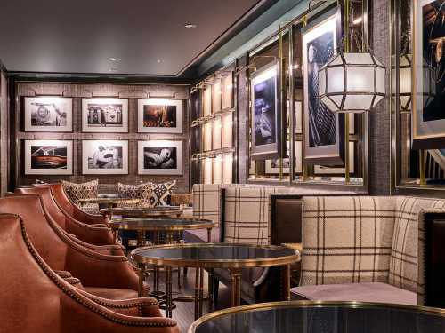 Elegant lounge with leather chairs, plaid accents, and framed black-and-white photos on the walls. Cozy atmosphere.