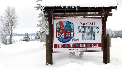 Sign for McCall Activity Barn, featuring activities like tubing, skiing, riding, and sliding, surrounded by snow.