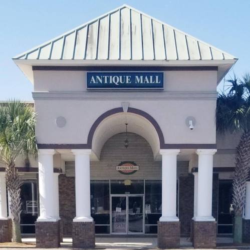 Front view of an Antique Mall with a green metal roof and columns, featuring a sign that says "Antique Mall."