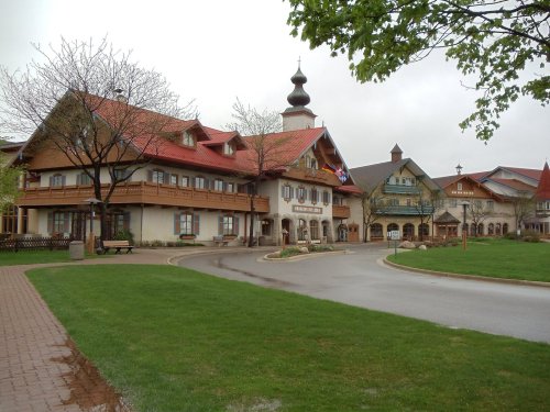 A charming village with European-style architecture, featuring colorful buildings and lush green lawns.