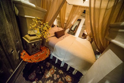 Cozy bedroom with a bed draped in sheer fabric, a small table, and decorative flowers, creating an inviting atmosphere.