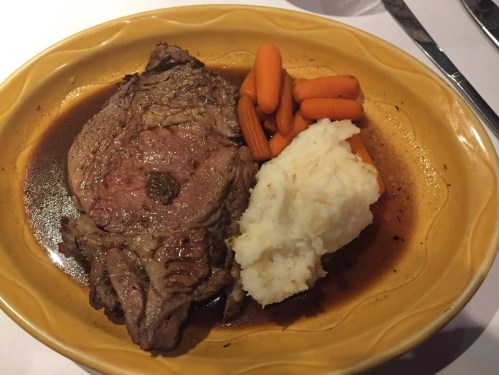 A plate of roast beef with gravy, mashed potatoes, and steamed carrots.