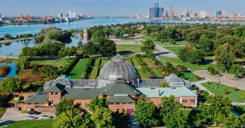 Aerial view of the Detroit Botanical Garden, showcasing the glasshouses and surrounding parkland. City skyline visible in the background. BELLE ISLE, DETROIT, MICHIGAN, UNITED STATES