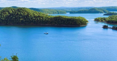 View of Dale Hollow Lake in Kentucky, featuring pretty blue waters, a boat, and surrounded by lush islands.