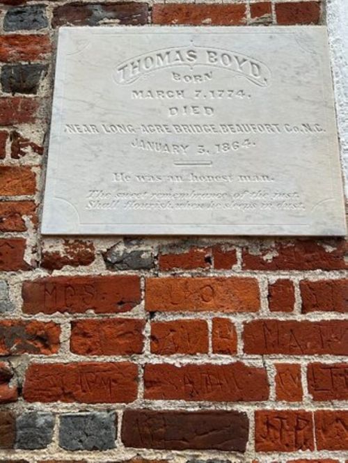 Plaque on a brick wall honoring Thomas Boyd, born March 7, 1774, died January 3, 1864, describing him as an honest man.