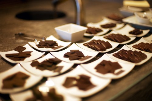 A variety of chocolate samples arranged on white plates, displayed on a countertop.
