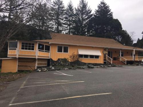 A single-story orange building with a sloped roof, surrounded by trees and a parking lot.