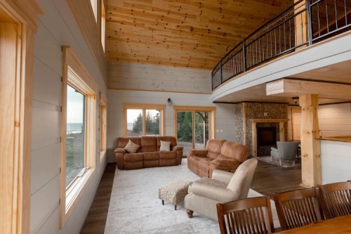 Cozy living room with high wooden ceilings, large windows, and comfortable seating, overlooking a scenic view.
