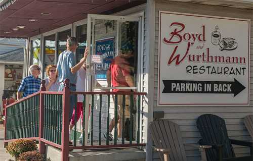 A group of people entering Boyd and Wurthmann Restaurant, with a sign indicating parking is in the back.