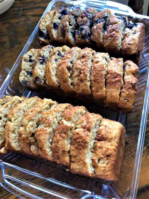 Three loaves of sliced bread in a glass dish, featuring different flavors with a golden-brown crust.