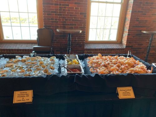 A seafood display featuring oysters on one side and a shrimp cocktail on the other, set on a black tablecloth.