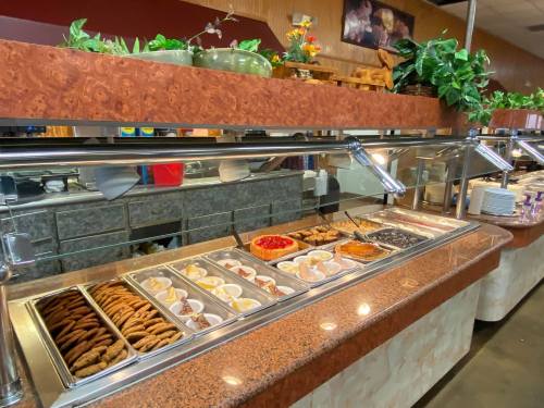 A buffet display featuring various desserts, including cookies, pastries, and fruit toppings, in a restaurant setting.