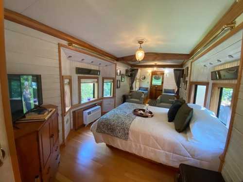 Cozy bedroom with two beds, a TV, and large windows, featuring wooden accents and warm lighting.