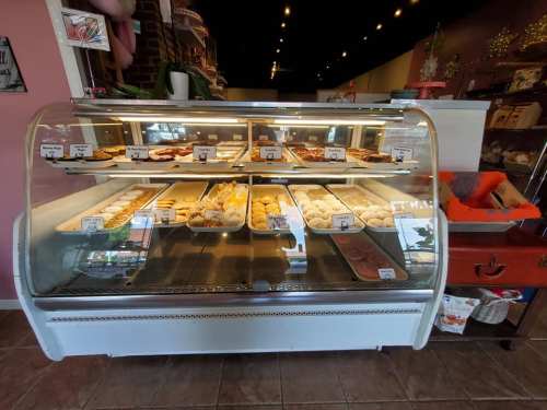 A display case filled with various baked goods, including cookies and pastries, in a cozy bakery setting.