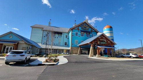 A colorful building with a blue exterior, featuring a large entrance and a striped silo, set against a clear blue sky.
