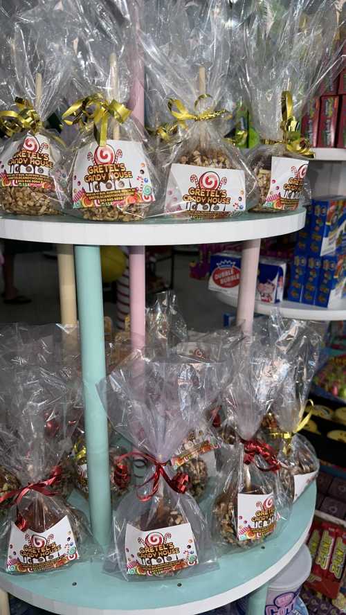 A display of colorful, wrapped treat bags on a tiered shelf, featuring festive labels and decorative ribbons.