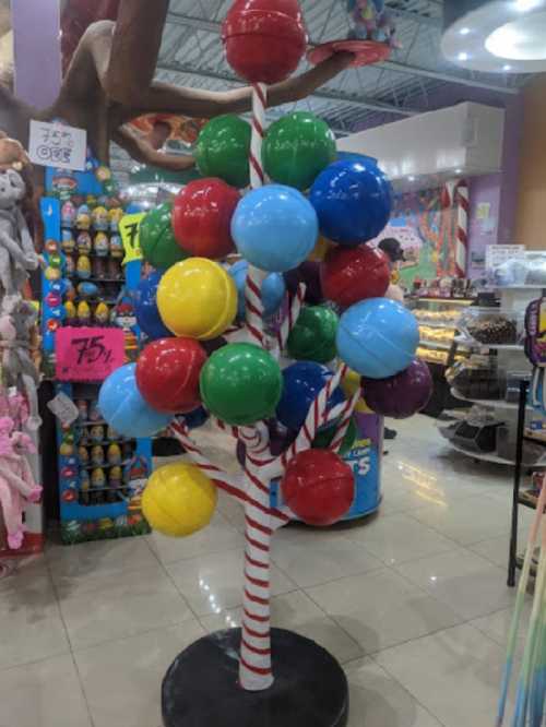 A colorful tree made of large, round lollipops in various colors, set in a playful store environment.