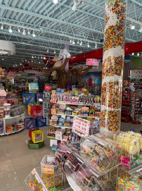 A colorful candy store filled with various sweets, toys, and a large candy display in the center.