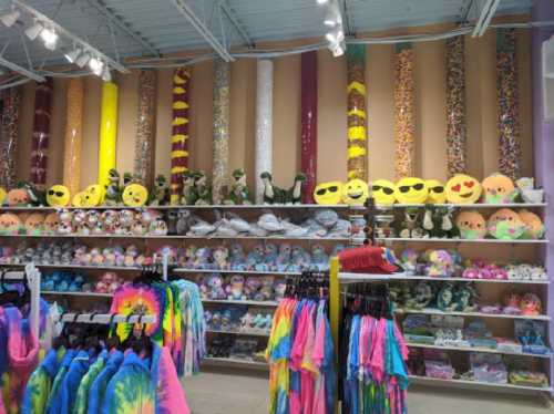 A colorful store display featuring plush toys, tie-dye clothing, and decorative items on shelves and walls.