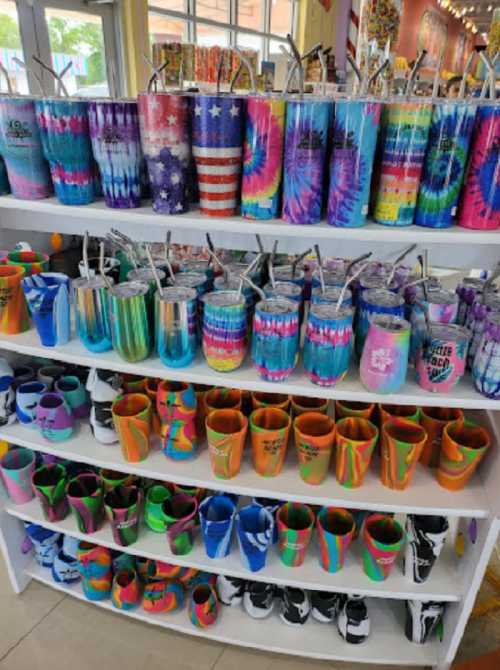 A display of colorful drinkware and tumblers in various designs, arranged on shelves in a vibrant store.