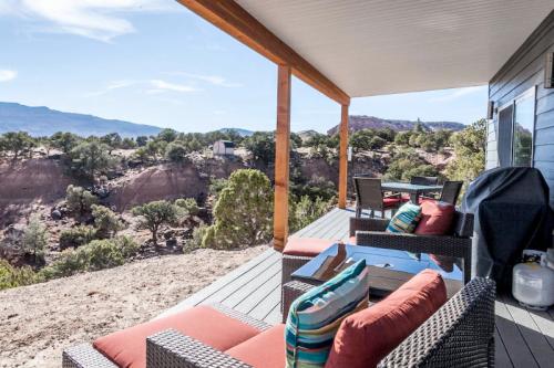 A scenic view from a porch with outdoor furniture overlooking a rocky landscape and distant mountains.