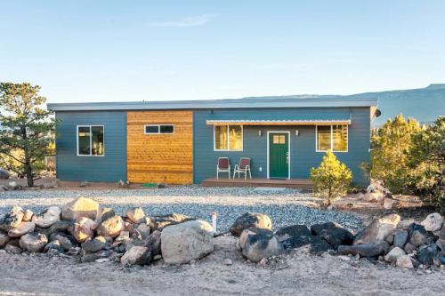 Modern single-story house with a wooden accent, surrounded by gravel and rocks, set against a mountainous backdrop.