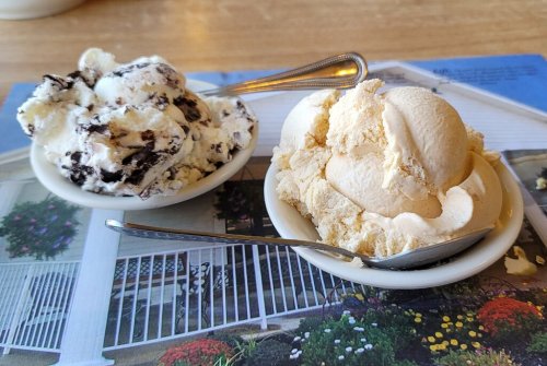Two bowls of ice cream: one with cookies and cream, the other with vanilla, on a colorful table setting.